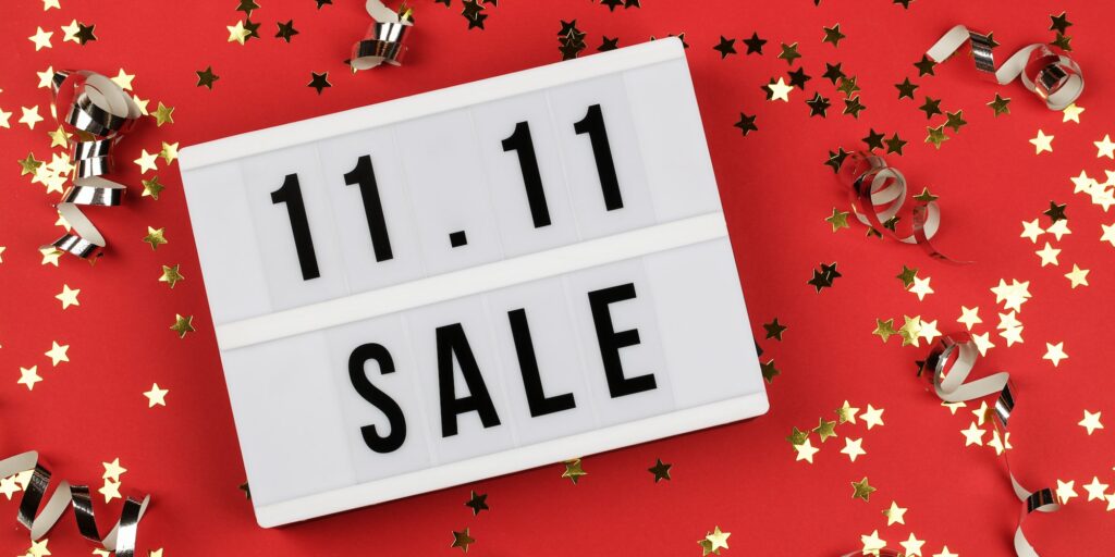 11.11 sale text on white lightbox, holiday ribbon and small stars on red background. Online shopping