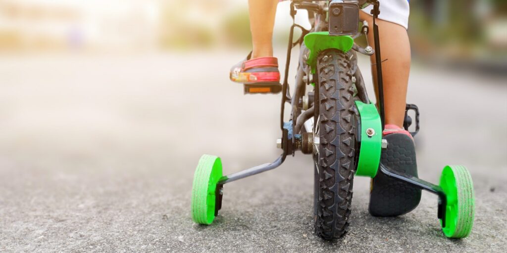 A child riding a bike with training wheels on the road.