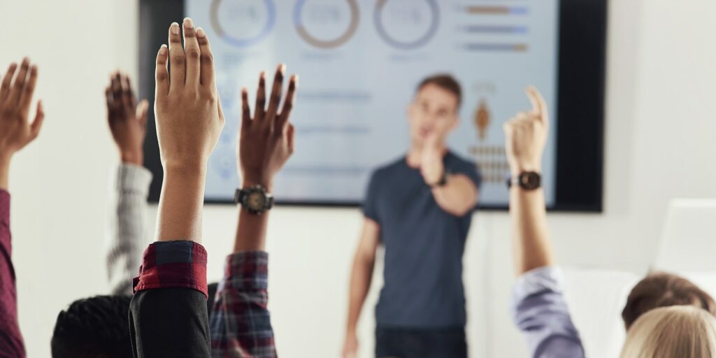By a show of hands. Cropped shot of a group of people raising their hands in a class.