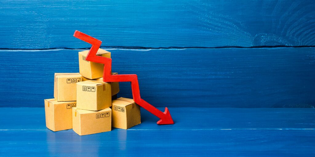Cardboard boxes and red down arrow. Fall in sales and production of goods