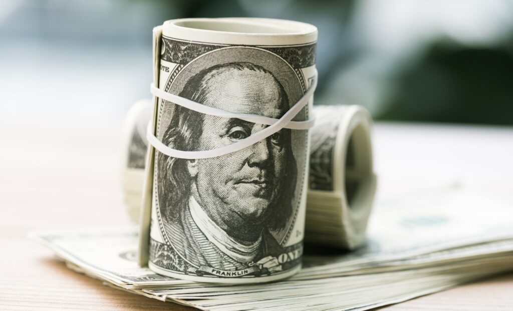 close up view of dollar banknotes in rolls with rubber band on table