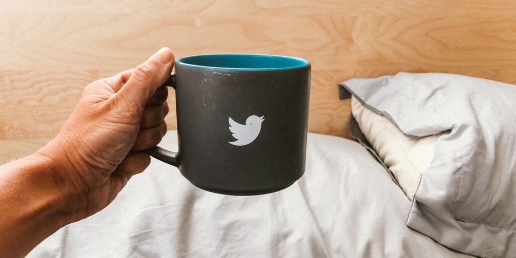 Hand holding mug with a tweeter bird sign