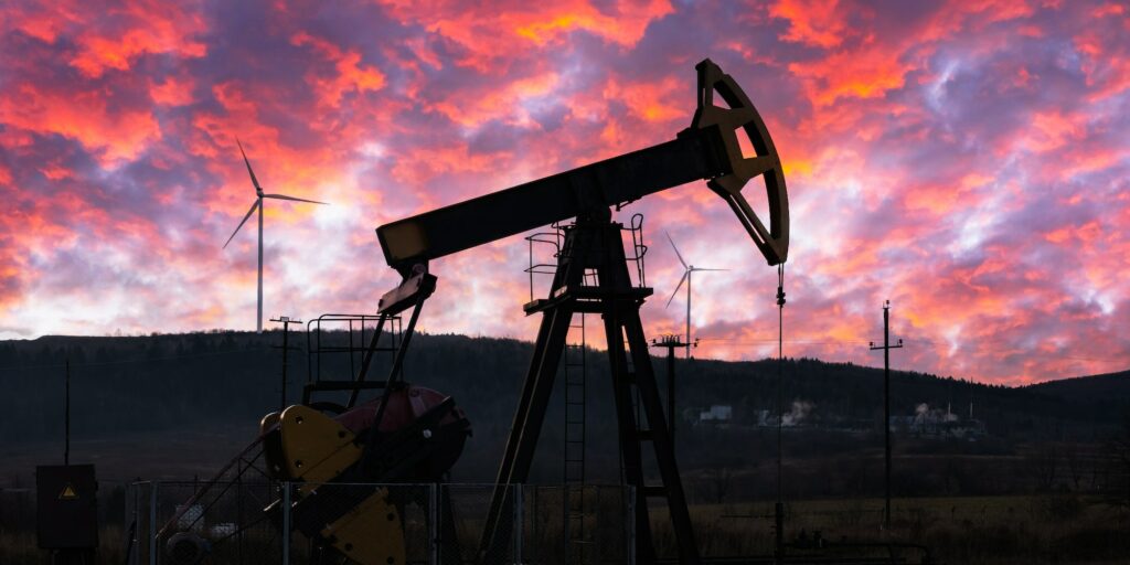 Oil pump and wind turbines against incredible purple sunset sky