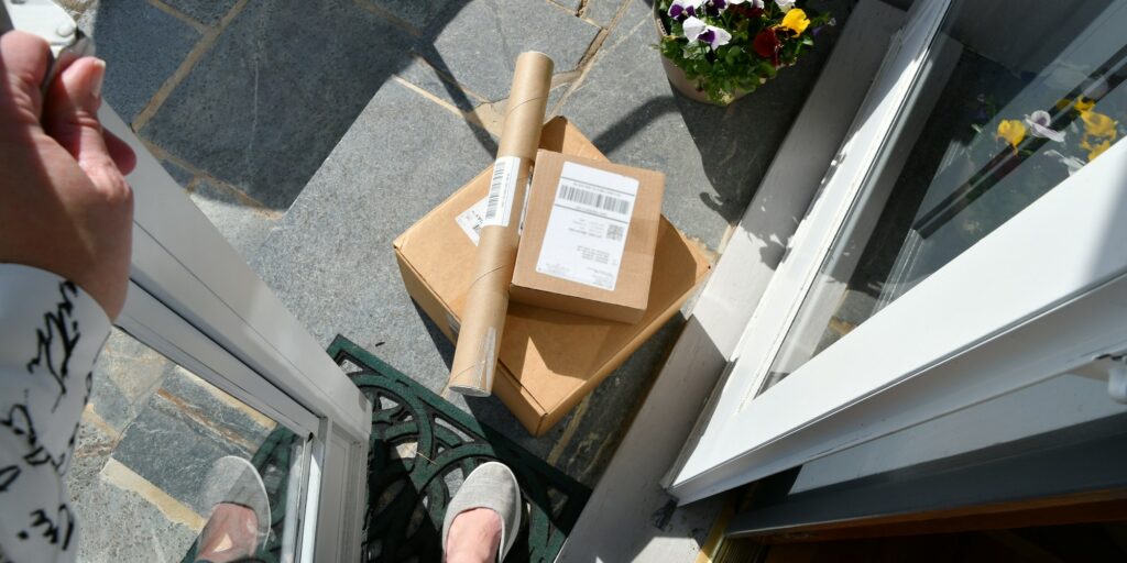 Woman stepping out front door to get packages boxes on porch that have been delivered overhead view