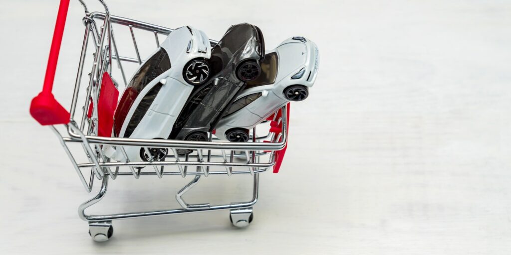 Trolley cart full of toy cars Tesla on a white background