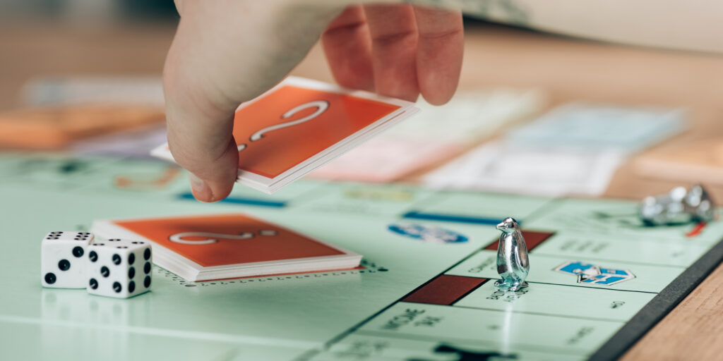 KYIV, UKRAINE - NOVEMBER 15, 2019:Cropped view of woman holding card by dices on monopoly game