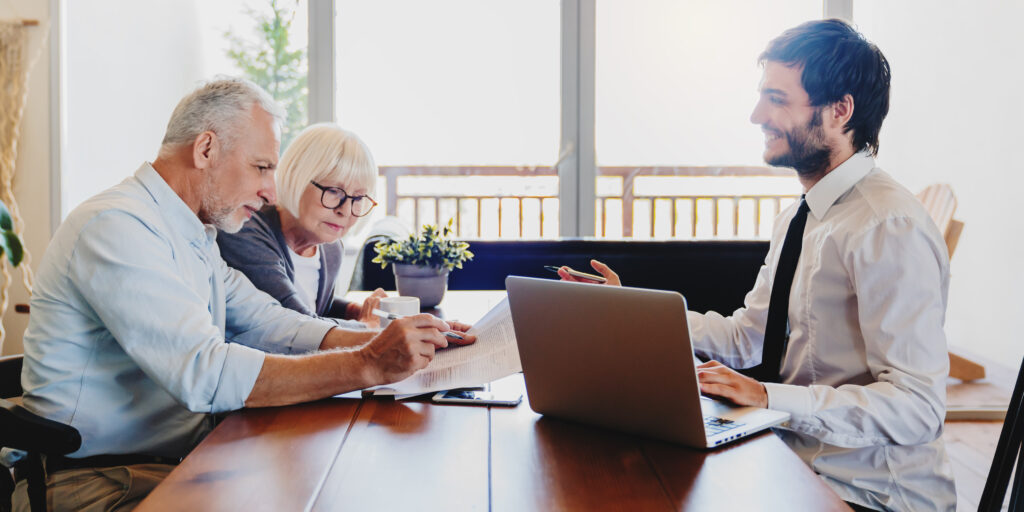 Senior couple planning their investments with financial advisor in living room at home
