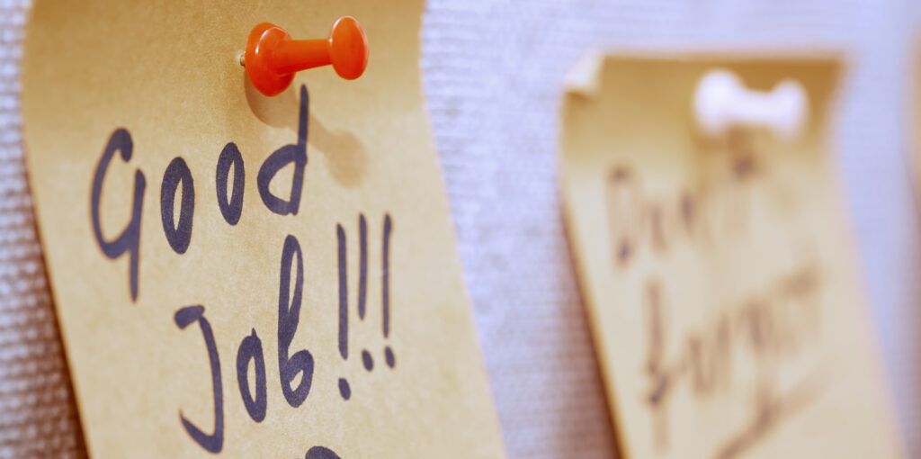Adhesive note with Good Job text on a cork bulletin board
