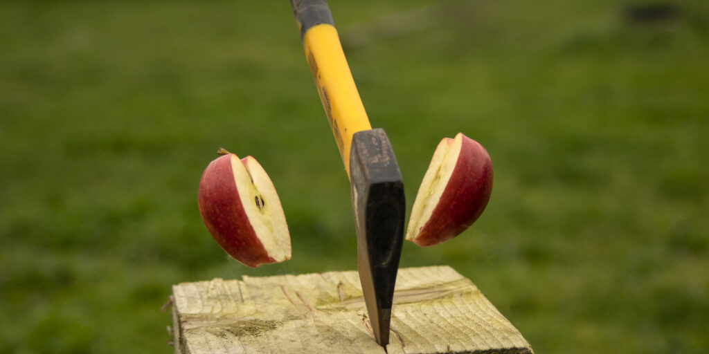 Shot of axe splitting an red apple in a two slice