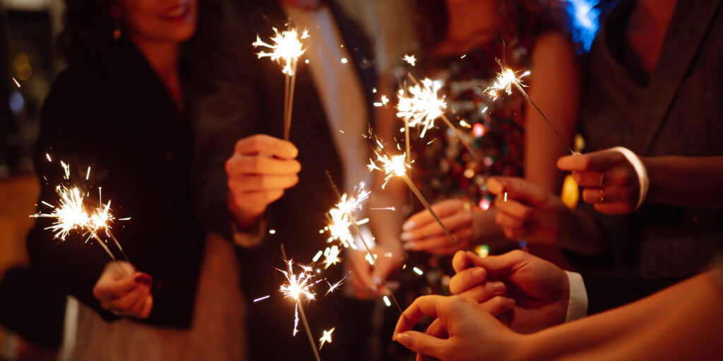 Sparkling sparklers in hands. Playing firework to celebrate winter holidays with friends at party