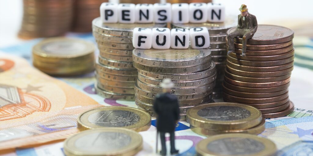 A pensioner stands in front of coin towers with the inscription pension fund