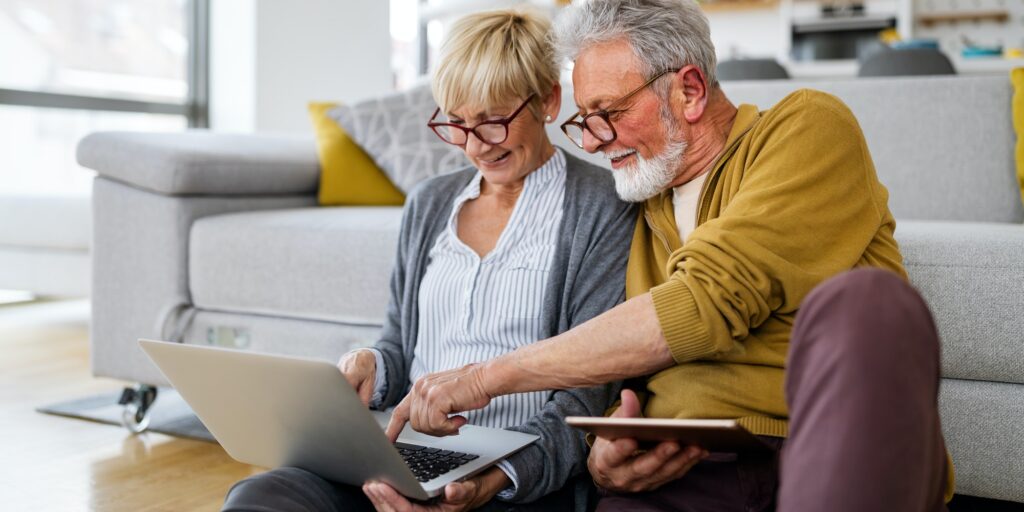Cheerful senior couple using technology devices and having fun at home