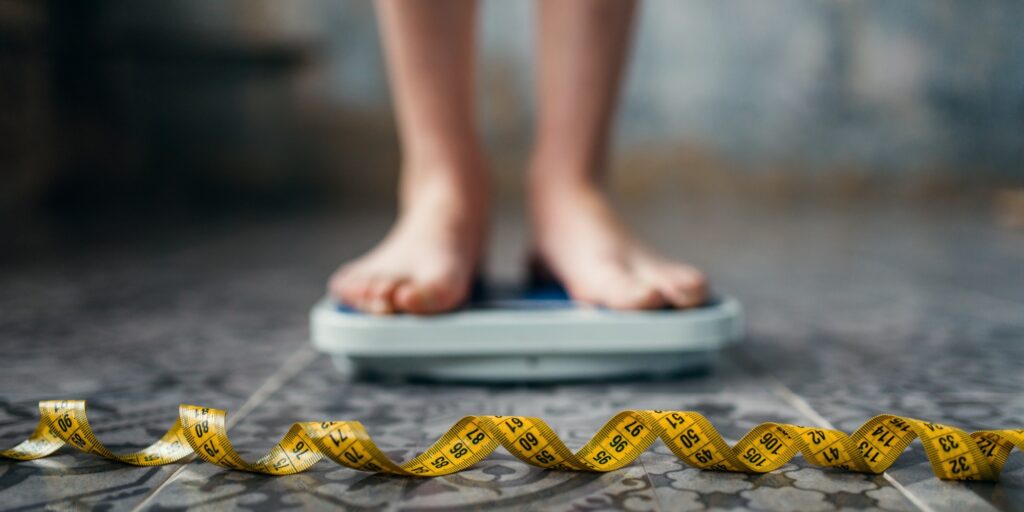Female feet on the scales, measuring tape