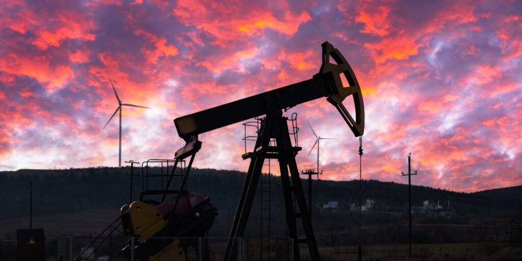 Oil pump and wind turbines against incredible purple sunset sky