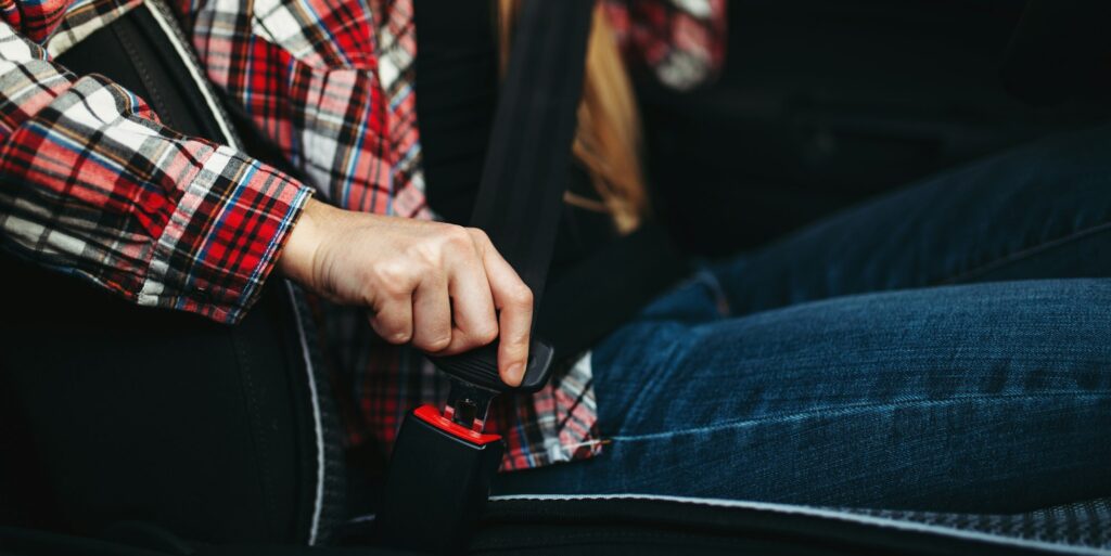 Woman driver fastens her seat belt in the car