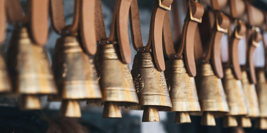 Brass bells hanging outside on leather straps