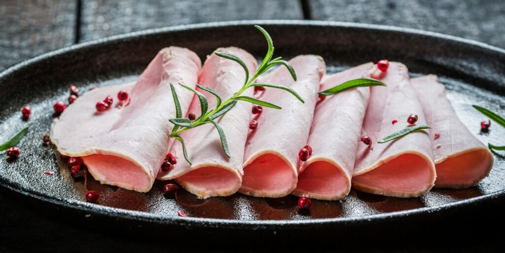 Closeup of fresh ham on black buried board