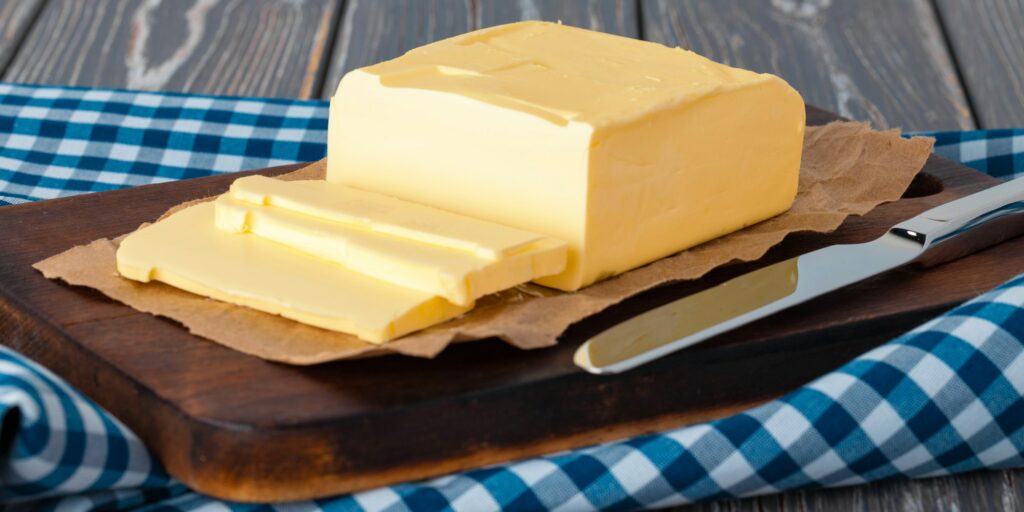 Wooden board with butter on blue checkered napkin