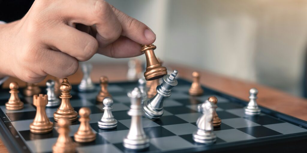 Businessman playing chess game beat opponent with strategy concept.