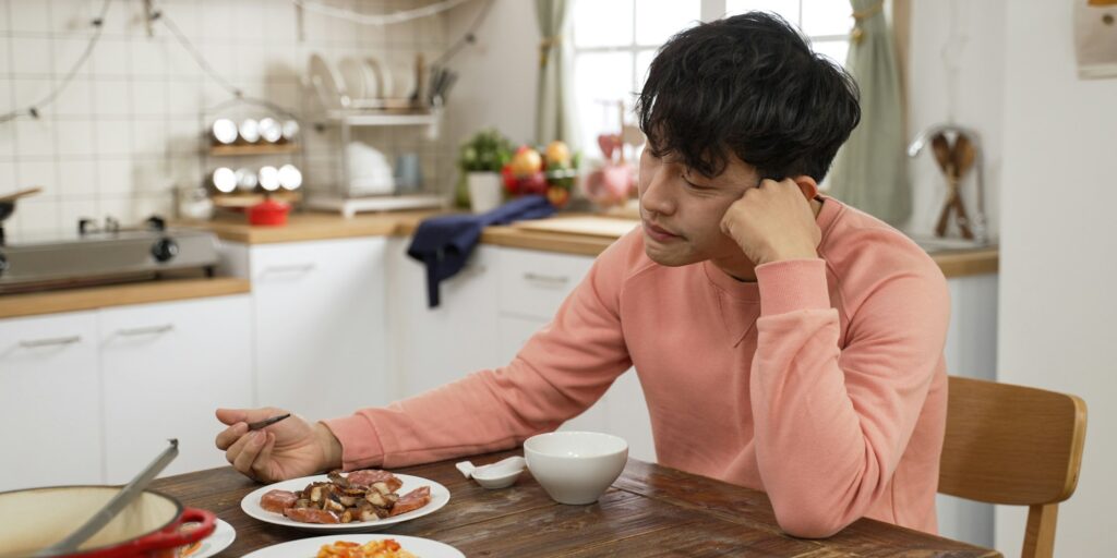 sad single asian male having lunch alone