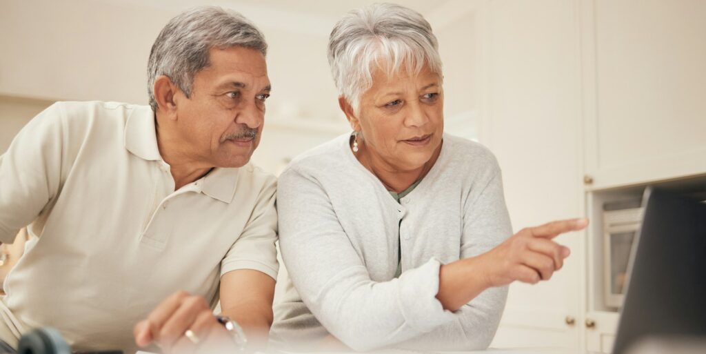 Senior couple, laptop and pointing in budget planning, finance or retirement together at home. Matu