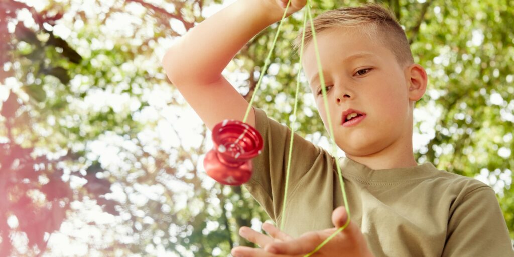 Low angle view of boy playing with yo-yo looking down