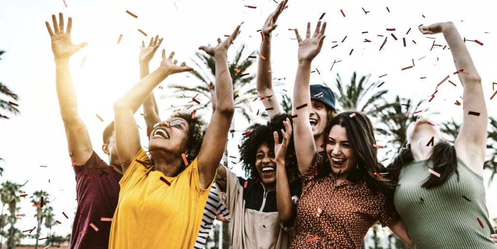 Group of friends enjoying party throwing confetti in the air