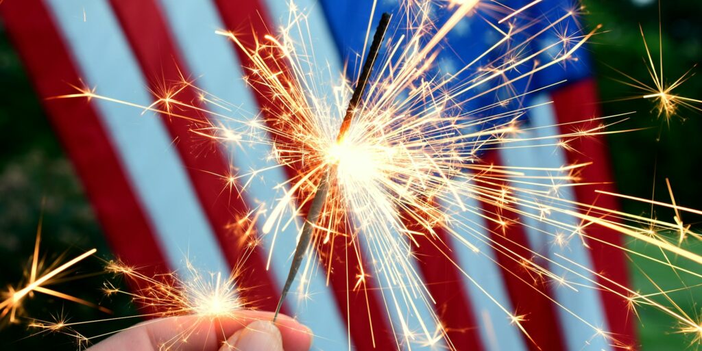 Holding a sparkler in front of an American Flag to celebrate the 4th of July Independence Day
