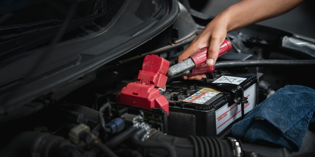 Car Machanic is maintenance on the car in the garage. checking and change the battery.