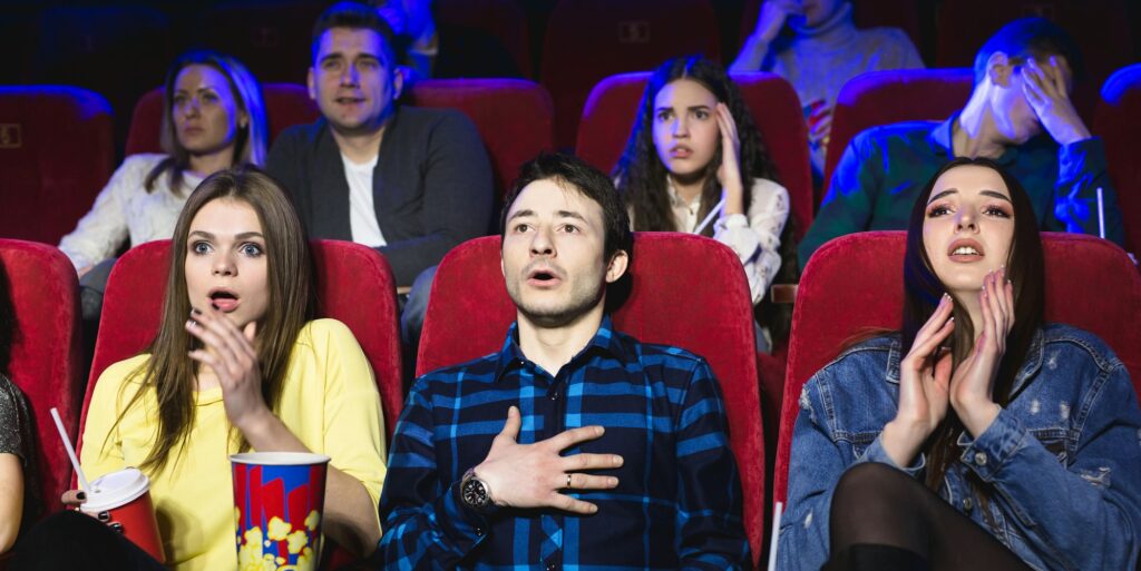 Group of people watch a horror movie at the cinema