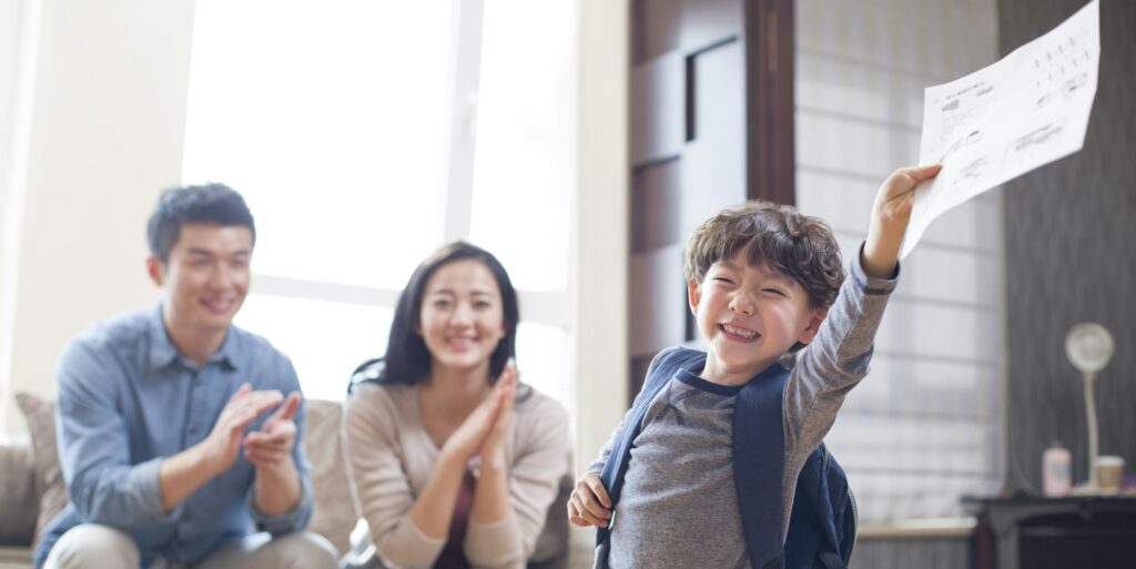 Happy boy coming home from school with a report card