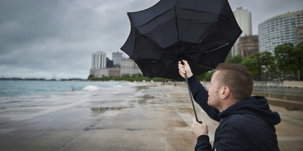 Man holding broken umbrella in strong wind