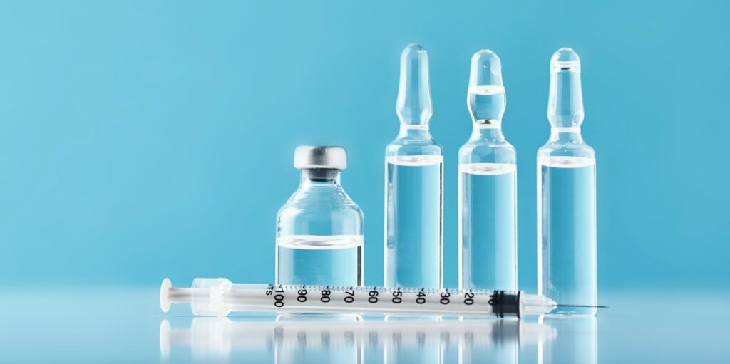 Syringes and medicine bottles with medication on a blue background