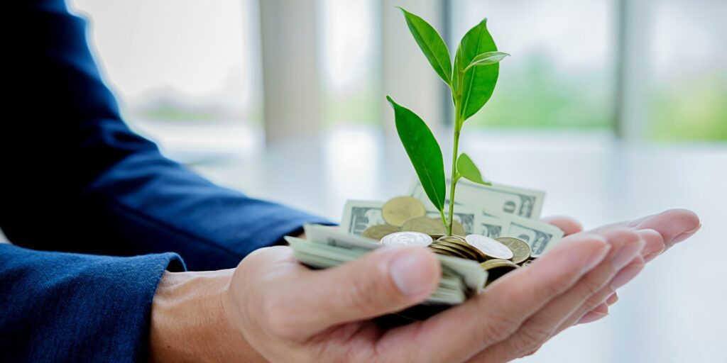 Close up of businessmen hands holding trees growth up on coin and banknote