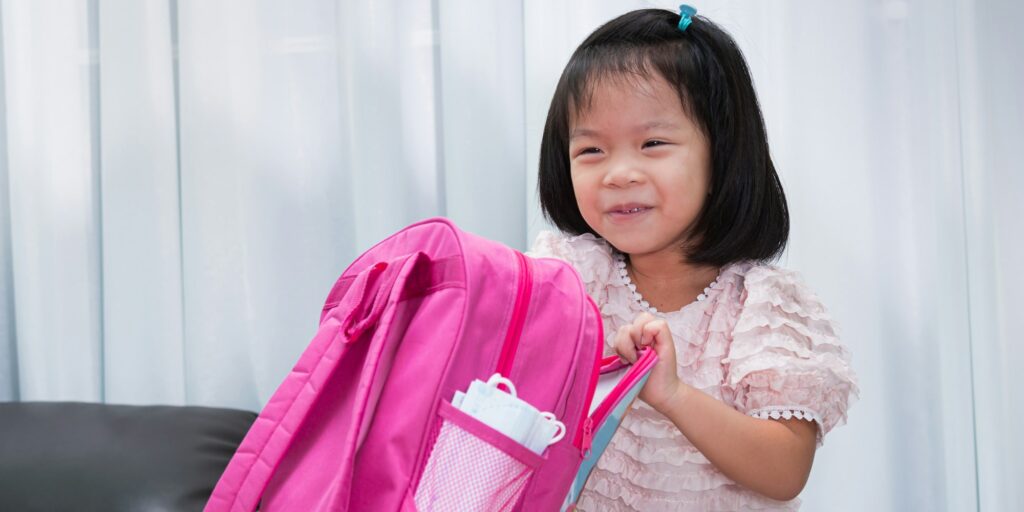 Kindergarten girl enjoyed preparing her pink school bags to go back to school.