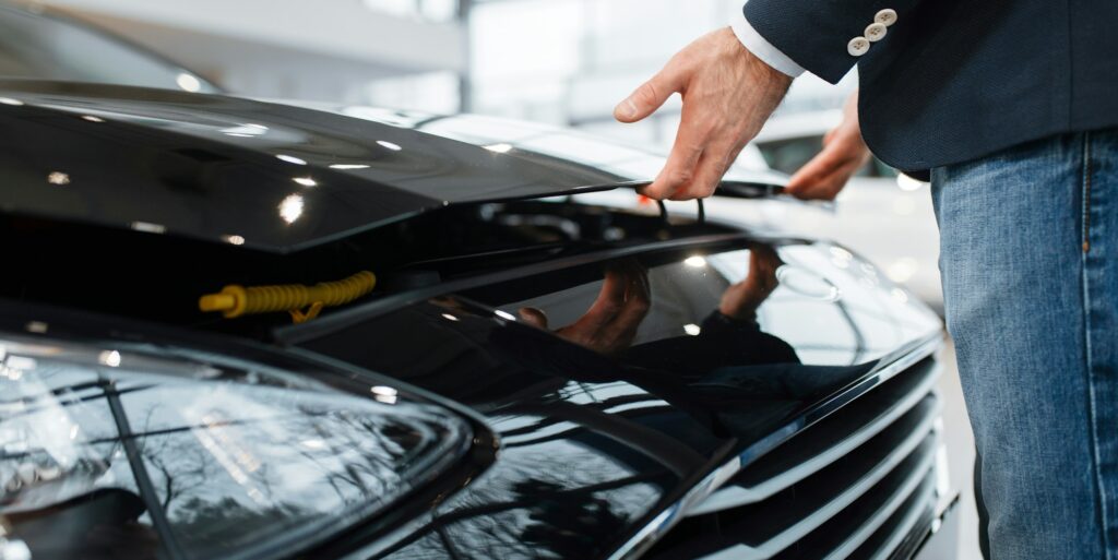Man opens hood of transport in car dealership