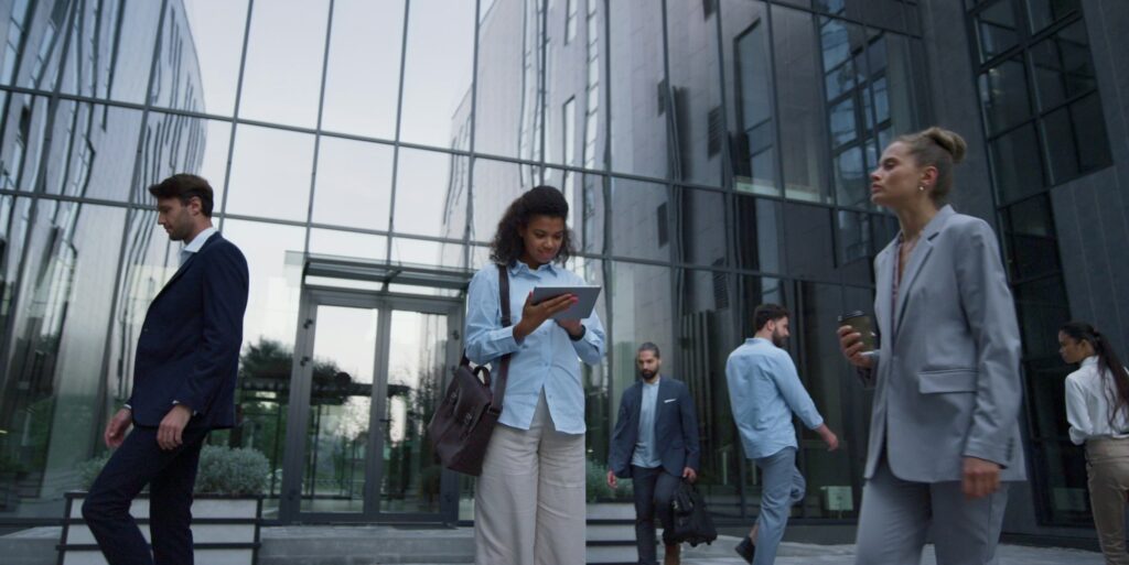 Focused woman use tablet in downtown area. Diverse employees rush to workplace.
