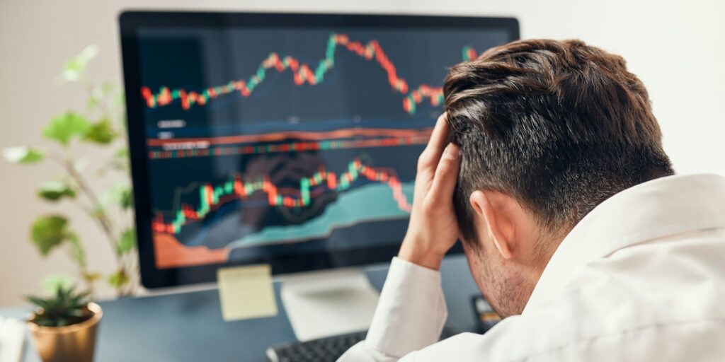 Worried businessman looking at charts stressed by news from stock market. Investor lost money online