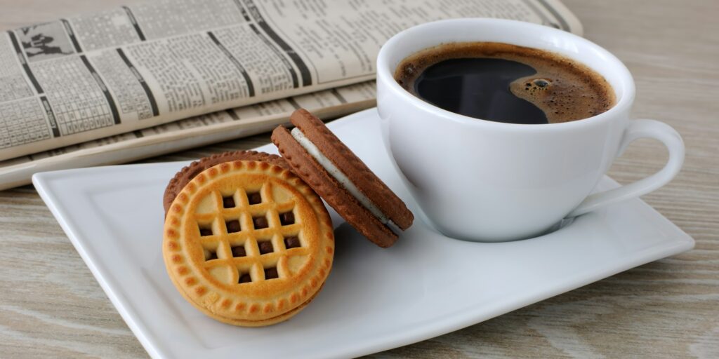 A cup of coffee and biscuits and a newspaper