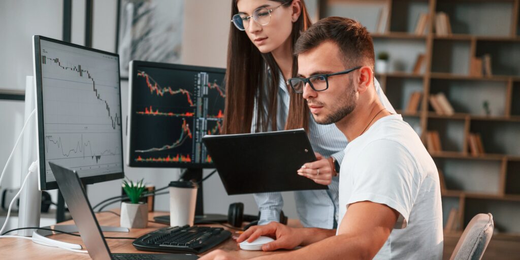 Analyzing information from computer screens. Two stock brokers is working together in the office