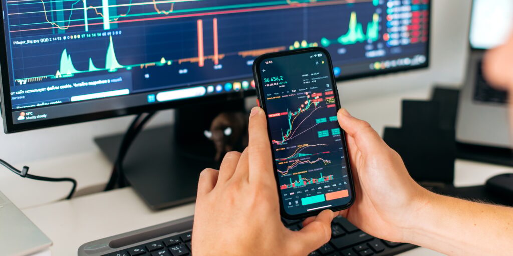 Online trading. Close-up of a smartphone in male hands, with trading data index chart graph on the