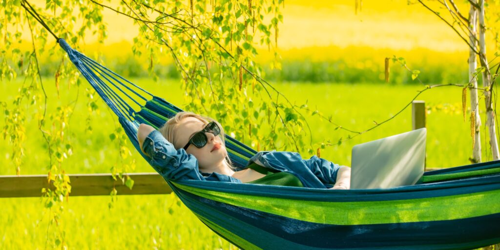 Woman in hammock working with laptop computer in hammock