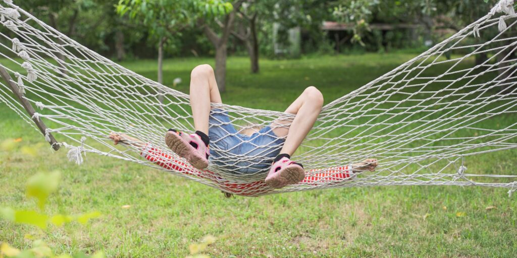 Child girl falling from hammock, spring garden background