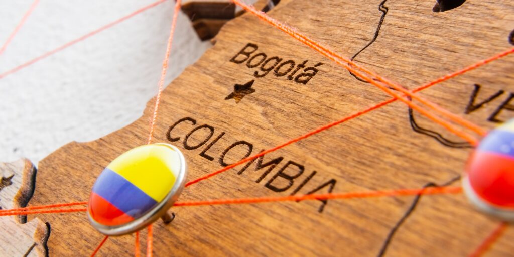 Colombia flag pins and red thread for traveling and planning trip.