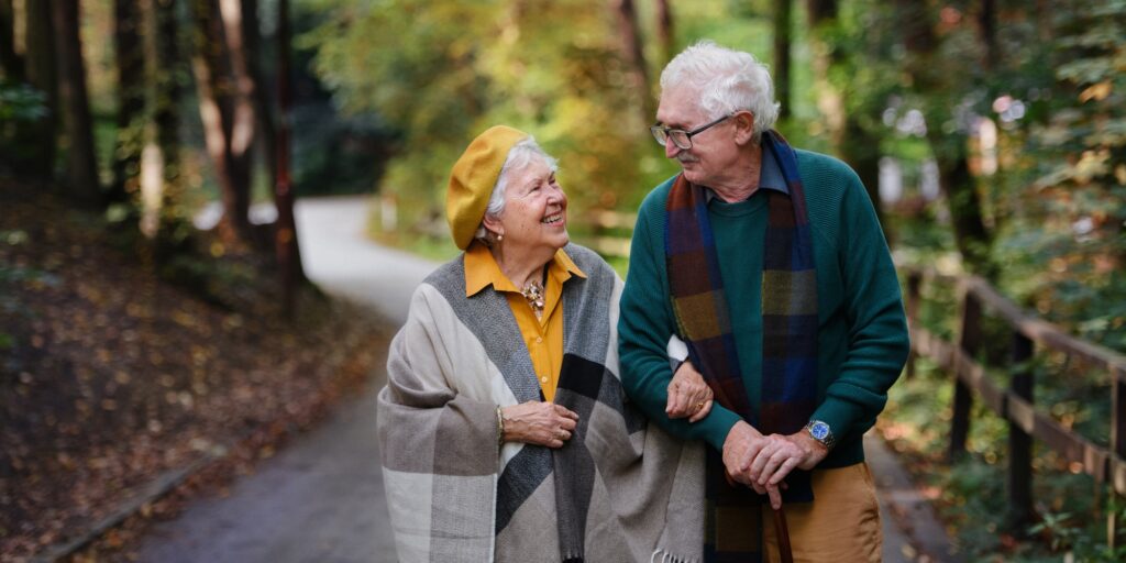 Happy senior couple in love walking in city park together.