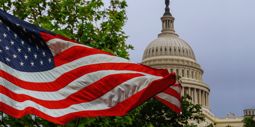 The US Capitol building with a waving American flag superimposed on the sky Capitol Hill in