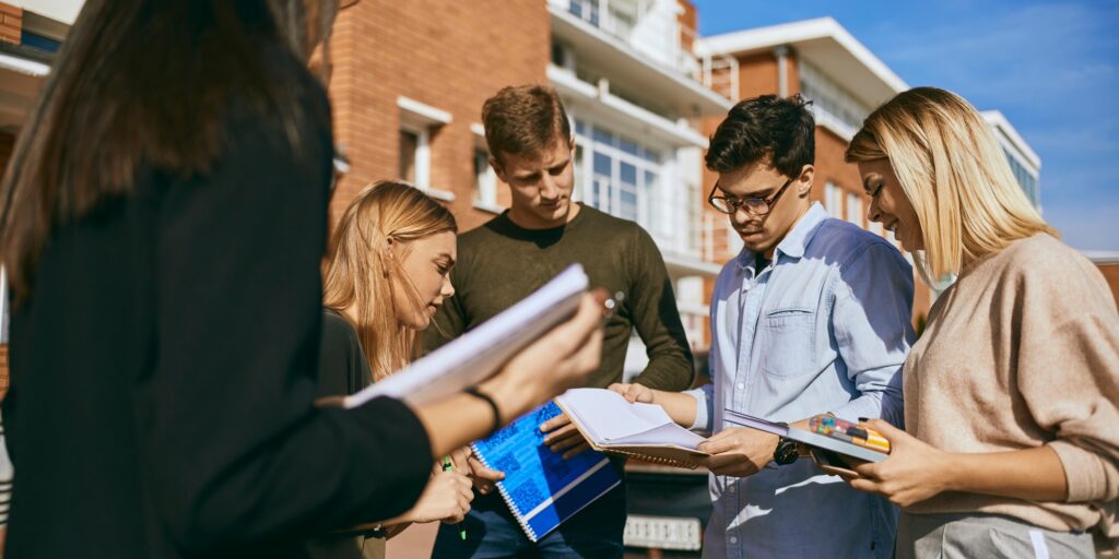 Group of students standing outdoors with documents