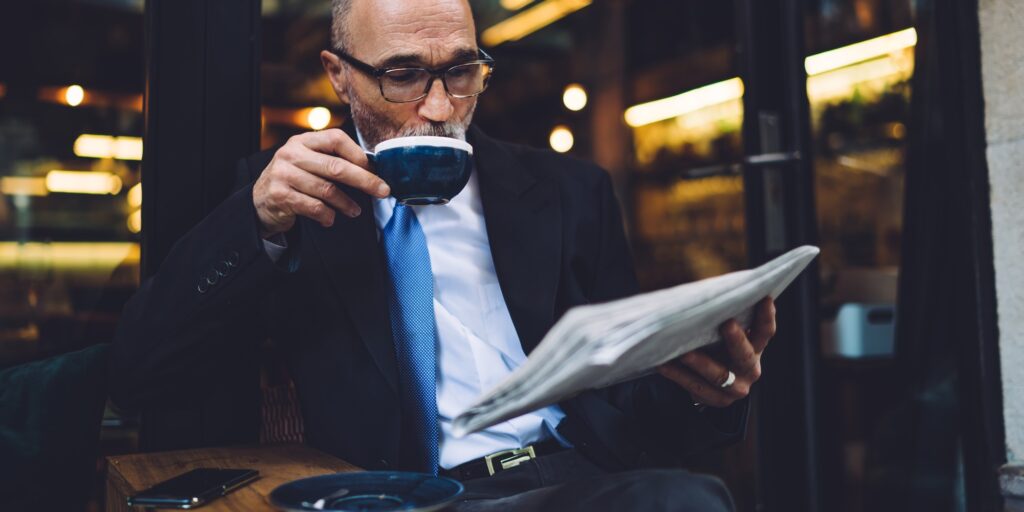 Senior businessman drinking coffee and reading newspaper