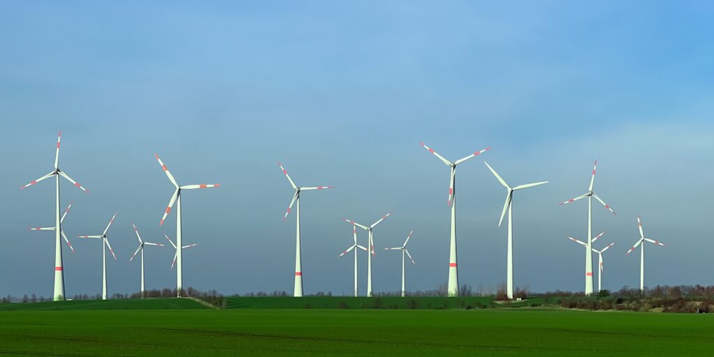 Wind energy stations in green field.