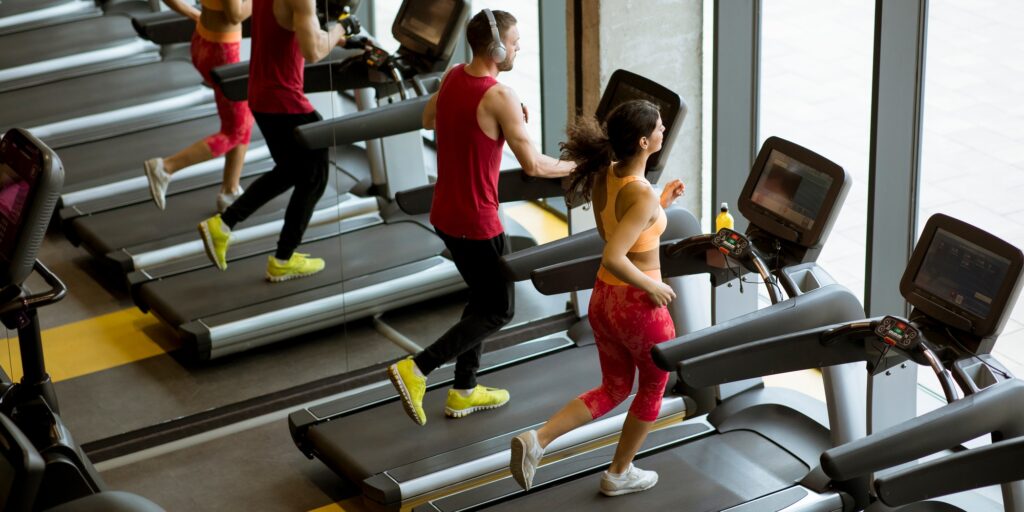 Couple run on treadmills in the gym